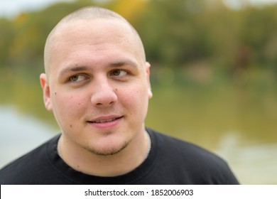 Close Up Frontal Head Shot Of A Thoughtful Young Man With Shaved Head And Stubble Looking Off To The Side In Contemplation