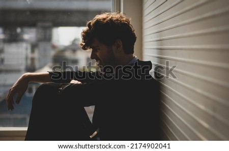 Close up of frustrated Caucasian businessman sitting on a floor with his knees up. Discouraged and hopeless expression. Financial problem, unemployment, bankruptcy concept.
