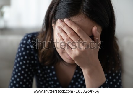 Close up frustrated depressed Asian woman covering face with hand, feeling lonely, crying, suffering from break up with boyfriend or divorce, bad relationship, mental psychological problem