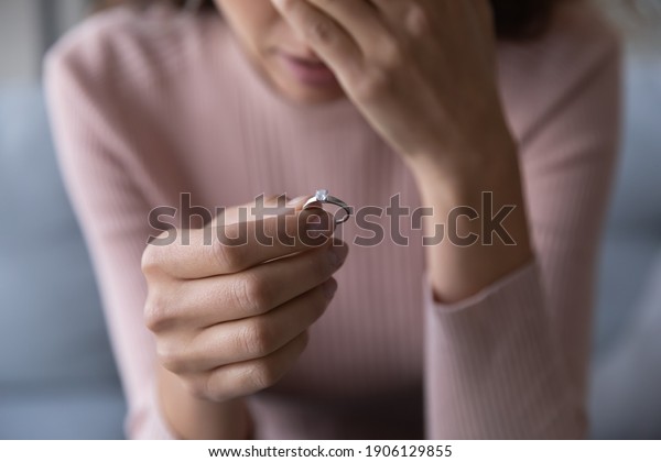 Close up frustrated millennial unhappy\
desperate woman holding engagement ring with diamond in hand,\
suffering from relations breakup or fiancee betrayal, denied\
marriage or getting\
divorced.