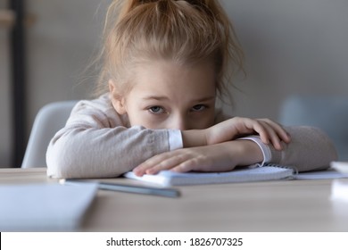 Close up frustrated unhappy little schoolgirl looking at camera, sitting at work desk at home, unmotivated girl distracted from school homework assignments, tasks, children education problem - Powered by Shutterstock