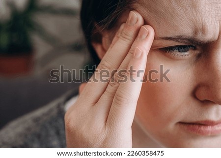 Close up of frustrated upset young brunette woman 20s coping with headache migraine concept feel anxiety pain pressure, mental stress, panic attack touching aching sore head sitting on couch at home [[stock_photo]] © 
