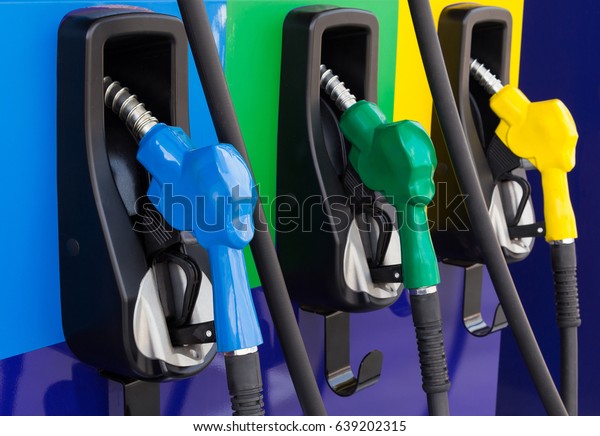 Close up fuel nozzle in oil dispenser with\
gasoline and diesel in service gas station. Pattern petrol pump gun\
filling blue green yellow colorful style. Concept feeling value of\
energy and business.