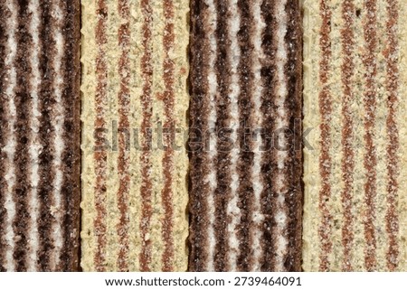 A close up full frame shot of four chocolate wafer sticks placed vertically side by side showing the detailed layers of dark cocoa biscuit and white cream