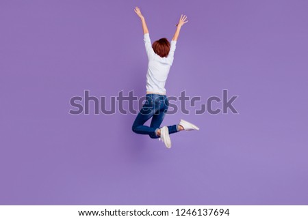 Close up full length size body rear behind view photo of high jumping pretty charming she her girl hands up in air wearing white casual sweater and jeans on violet background