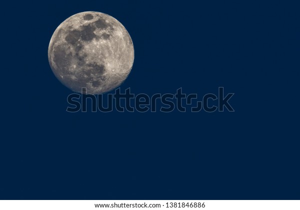 Close up of full moon against Blue sky featuring\
moon craters and seas