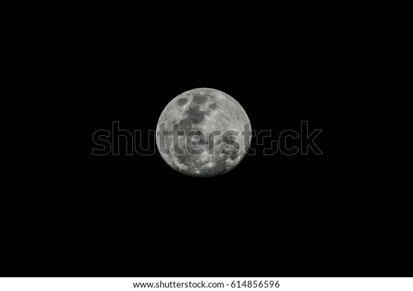 A\
close up of full moon over black sky. Black and\
white.