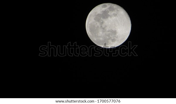 Close up of full moon seen from earth.\
Showing detail of moon surface. dark\
background.