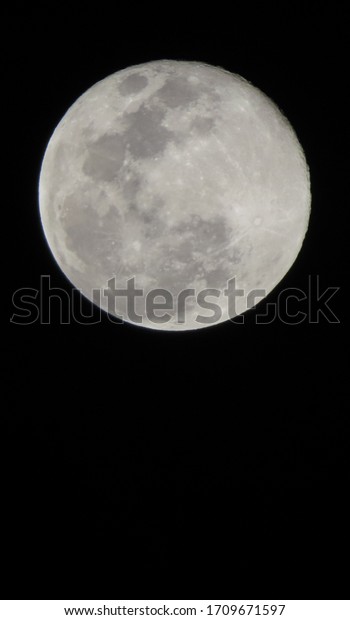 Close up of full moon seen from earth.\
Showing detail of moon surface. dark\
background.