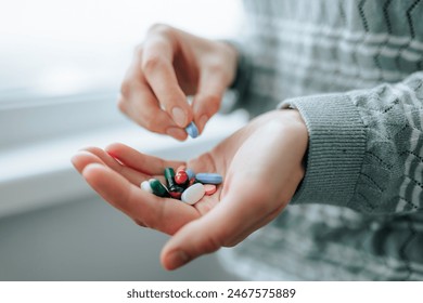 Close up full palm tablets of different shapes, different sizes, enzymes, analgesics, painkillers, antibiotics. Unrecognizable woman takes medication, 