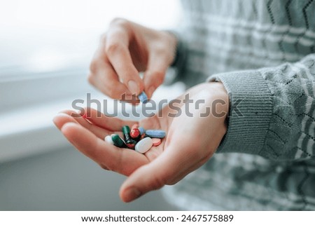 Close up full palm tablets of different shapes, different sizes, enzymes, analgesics, painkillers, antibiotics. Unrecognizable woman takes medication, 