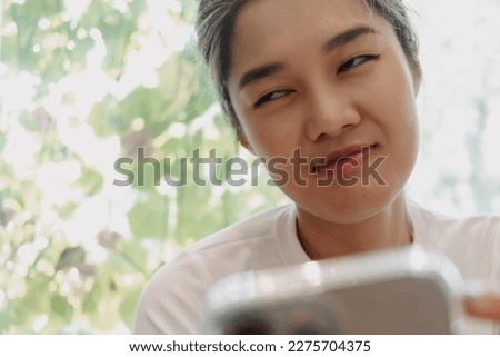 Close up funny face asian woman reading flirt chat in the phone.