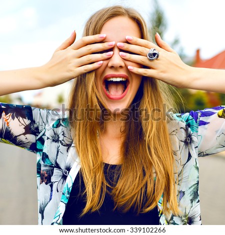 Close up funny portrait of smiling blonde girl close her eyes buy her hands, bright colors, positive emotions, cheerful youth concept.