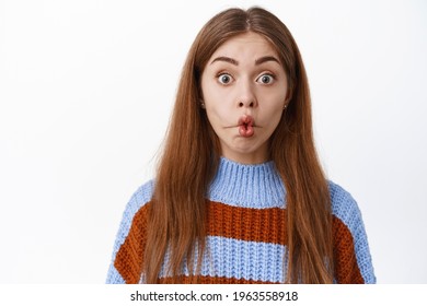 Close Up Of Funny Surprised Girl, Pucker Lips And Stare With Interest And Excitement At Camera, Standing In Sweater Against White Background