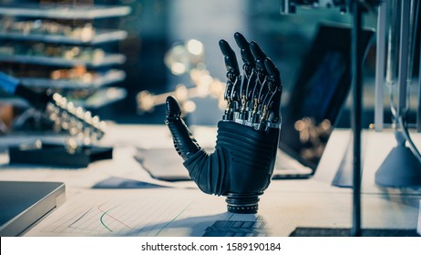 Close Up Of A Futuristic Prosthetic Robot Arm Stands On A Desk In A High Tech Research Laboratory With Modern Computer Equipment.