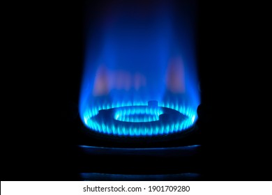 Close Up Of Gas Burner With Blue Flame On Kitchen Stove In Dark.