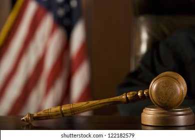 Close Up Of Gavel With American Flag In The Background In Courtroom