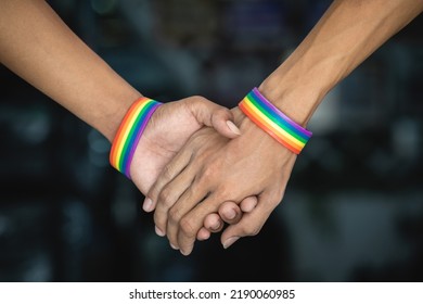 Close Up Of Gay Couple In Love Holding Hands, Walking Down The Street In Dark Background.