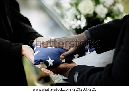 Close up of general handing folded American flag to woman at funeral ceremony for army veteran