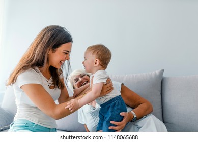 Close up of a generational family together in their living room at home, relaxing with the grandmother. Grandmother and mother in living room with baby smiling. Multi-generation family portrait