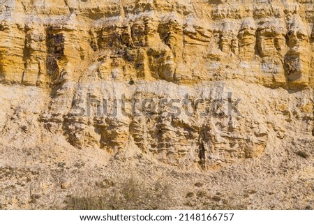 Close up of geological layers within yellow sandstone cliffs forming abstract patterns and textures