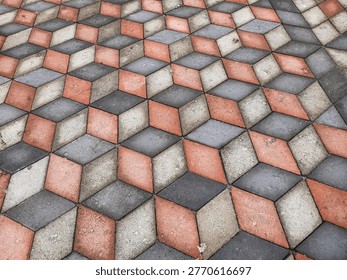 Close up of geometric interlocking pavement in red gray and white tones, captured outdoors in natural light, showing detailed stone texture for abstract background and design use.