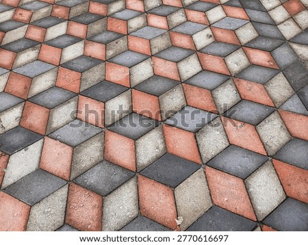Close up of geometric interlocking pavement in red gray and white tones, captured outdoors in natural light, showing detailed stone texture for abstract background and design use.