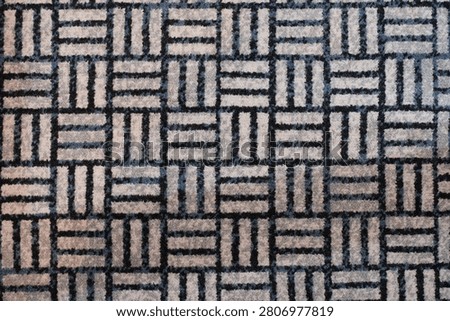 Close up of geometric patterned carpet with repeating square and line design in neutral tones.