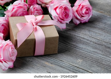 Close up of a gift box with pink roses in background on weathered wooden planks for Mothers day love holiday concept  - Powered by Shutterstock