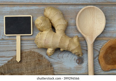 close up of ginger root on a old wooden planks background with wooden spoon and blackboard tag with empty copy space