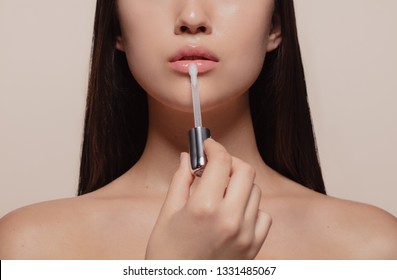 Close up of girl applying lip gloss. Cropped shot of woman applying lips makeup with cosmetic brush.