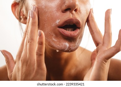Close up of girl with beautiful skin smearing face cream at the studio on a white backround - Shutterstock ID 2239335421
