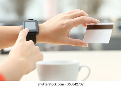 Close up of a girl hands buying on line with a credit card and a modern generic smart watch in a bar terrace - Powered by Shutterstock