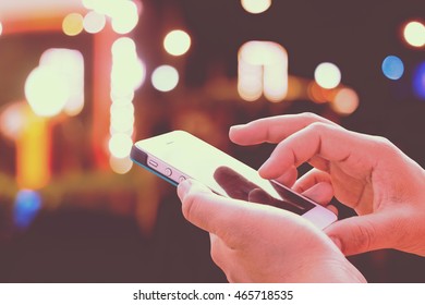 Close up of girl hands hoding modern smart phone , woman's hand using cellphone at night city, bokeh light