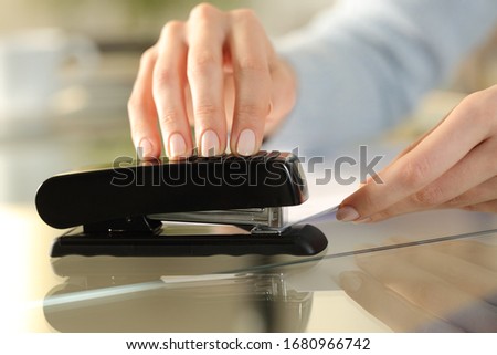 Close up of girl hands using stapler on documents over a desk at home