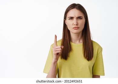 Close Up Of Girl Makes Confused Face, Dont Get It, Pointing Up, Frowning And Squinting Puzzled, Cant Understand Smth, Standing Against White Background