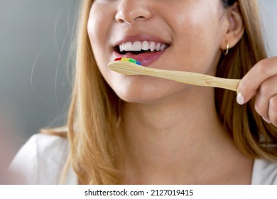 Close up of girl mouth with eco friendly bamboo toothbrush. Happy woman brushing teeth with wooden bamboo toothbrush.