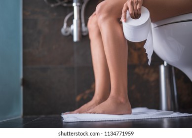 Close Up Girl Smooth Legs Locating In Lavatory On Cozy Carpet. She Keeping Bog Roll In Arm