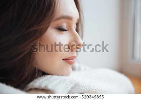 Close up girl in sweater near the window. eyes closed.