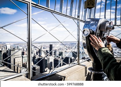 Close up of a girl that looks manhattan by telescope, from the Empire State Building