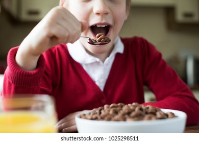 Close Up Of Girl Wearing School Uniform Eating Bowl Of Sugary Breakfast Cereal In Kitchen