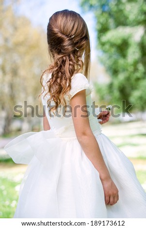 Close up of girl in white dress showing hairstyle outdoors.