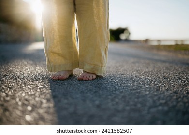 Close up of girl's barefoot legs in summer outfit on walk during summer vacation, yellow linen pants. - Powered by Shutterstock