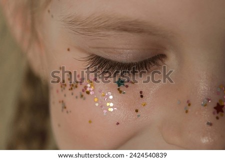 Close up of girl's closed eye with long lashes and glitters around