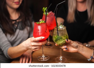 Close Up Of Girls Drinking Cocktails In Nightclub. Girls Having Good Time,cheering And Drinking Cold Cocktails, Enjoying Friendship Together In Bar, Close Up View On Hands.