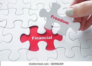 Close up of girl's hand placing the last jigsaw puzzle piece with word Financial Freedom - Shutterstock ID 383986309