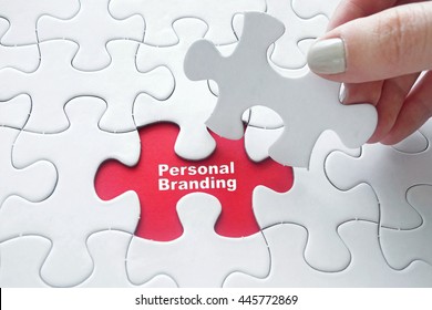 Close up of girl's hand placing the last jigsaw puzzle piece with word Personal Branding 