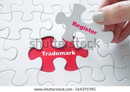 Close up of girl's hand placing the last jigsaw puzzle piece with word Register and Trademark