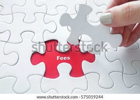 Close up of girl's hand placing the last jigsaw puzzle piece with word Fees