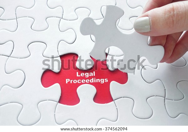 Close up of girl\'s hand\
placing the last jigsaw puzzle piece with word Legal Proceedings as\
law concept